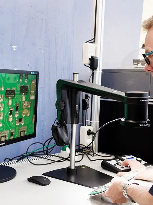 Man using a digital microscope to inspect PCBs