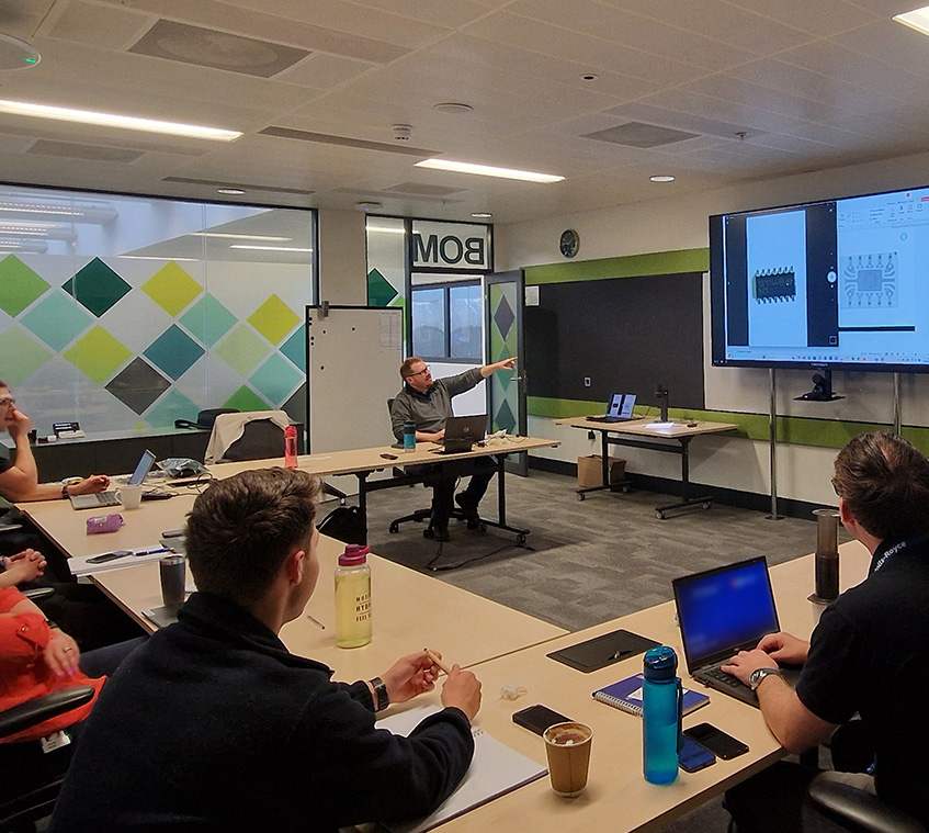 Class room location with electronic failure analysis professionals looking at a projector with live image from TAGARNO ZIP digital microscope
